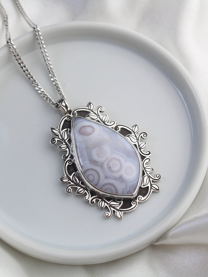 Handmade 925 sterling silver pendant with luna agate stone with orbicular patterns surrounded by hand-stamped and hand-sawed decorative branch accents lily and William jewelry